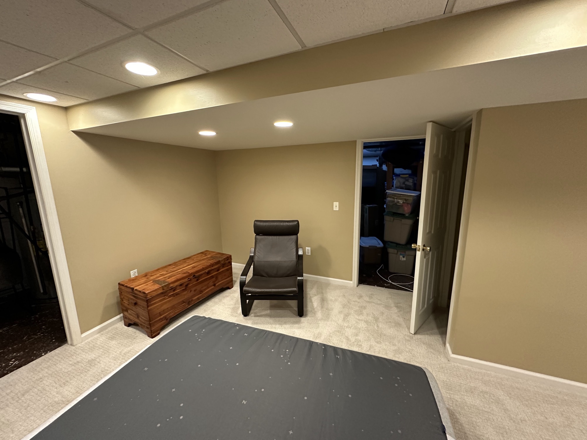 Finished basement room with tan walls and recessed lighting