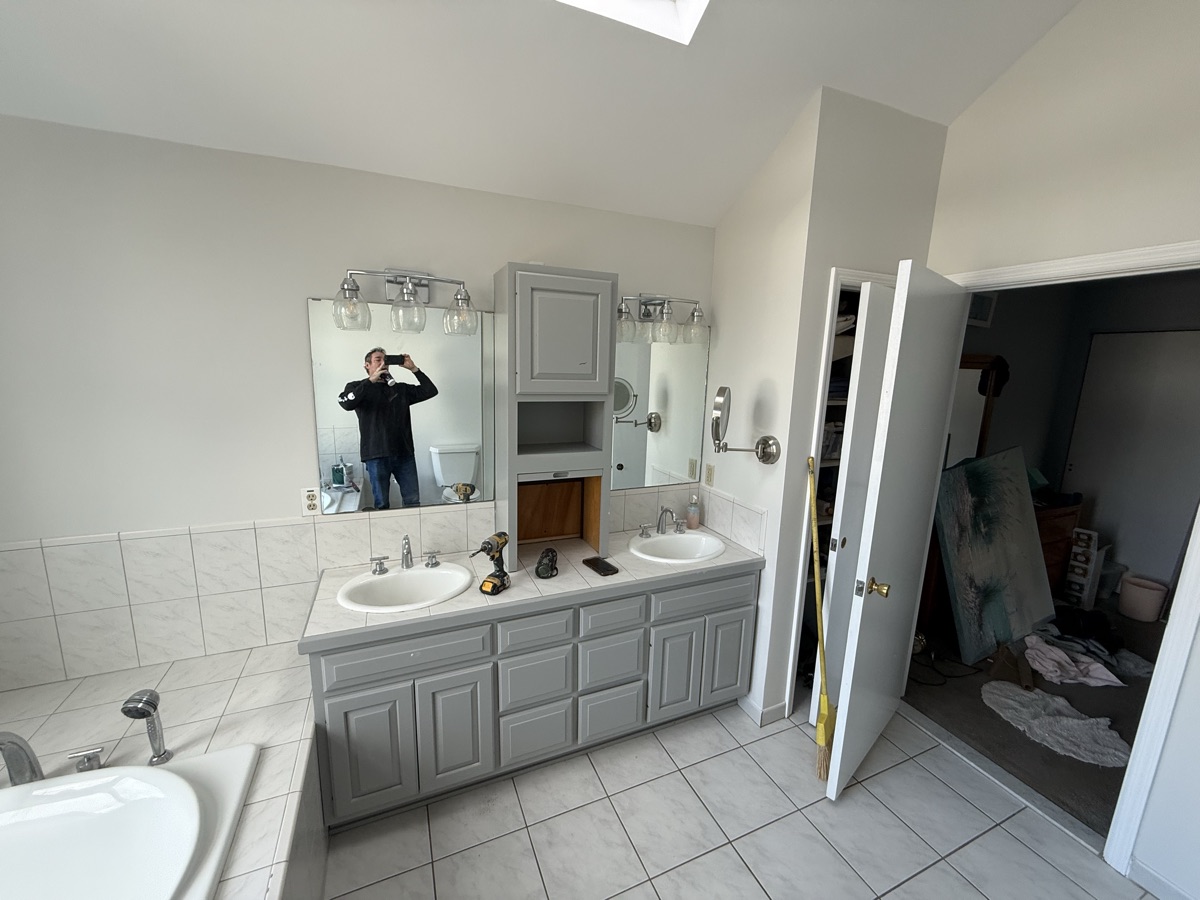 Full bathroom view with gray painted vanity and skylight