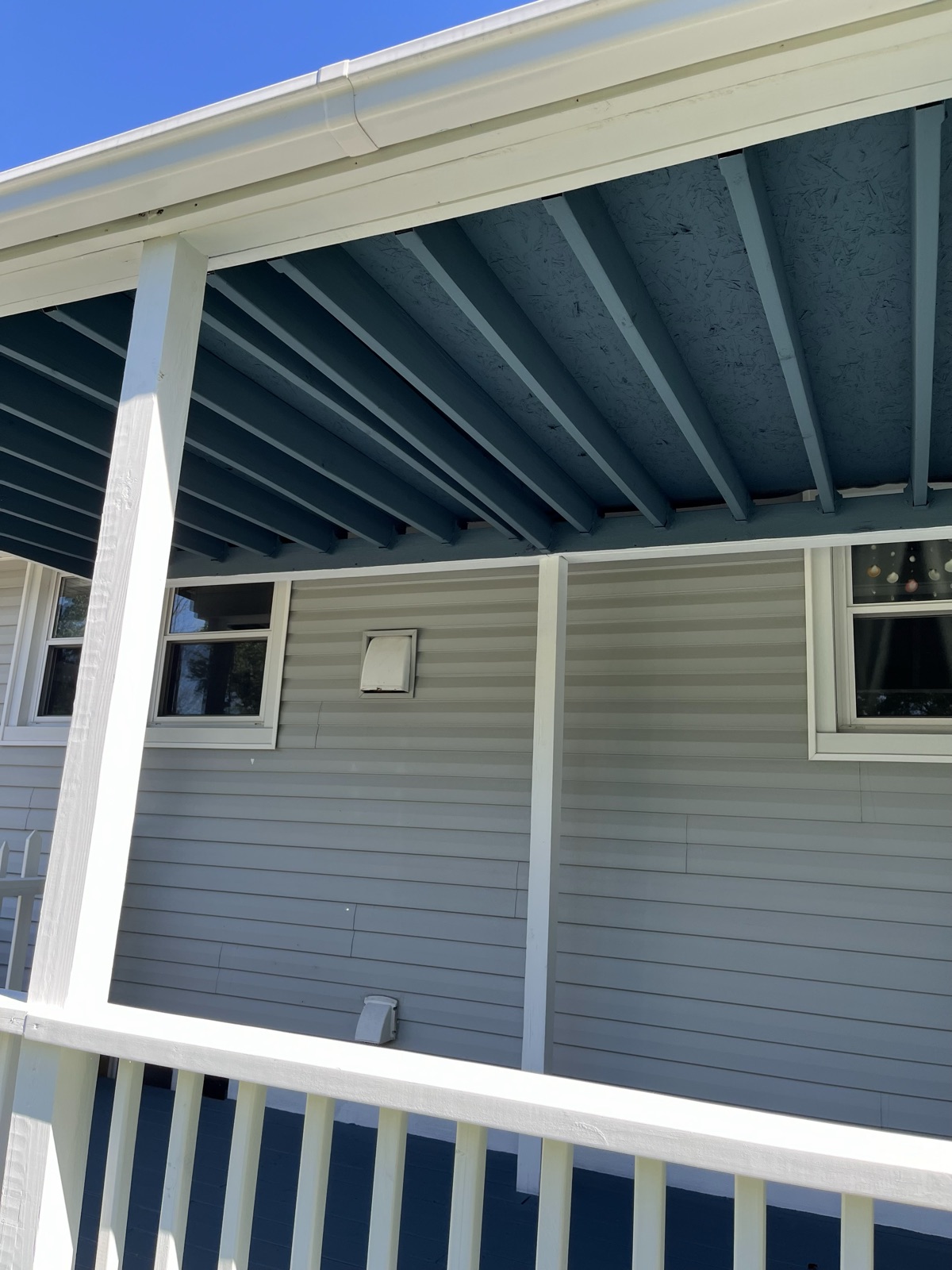 Covered porch with blue ceiling and white posts by J&B Painting