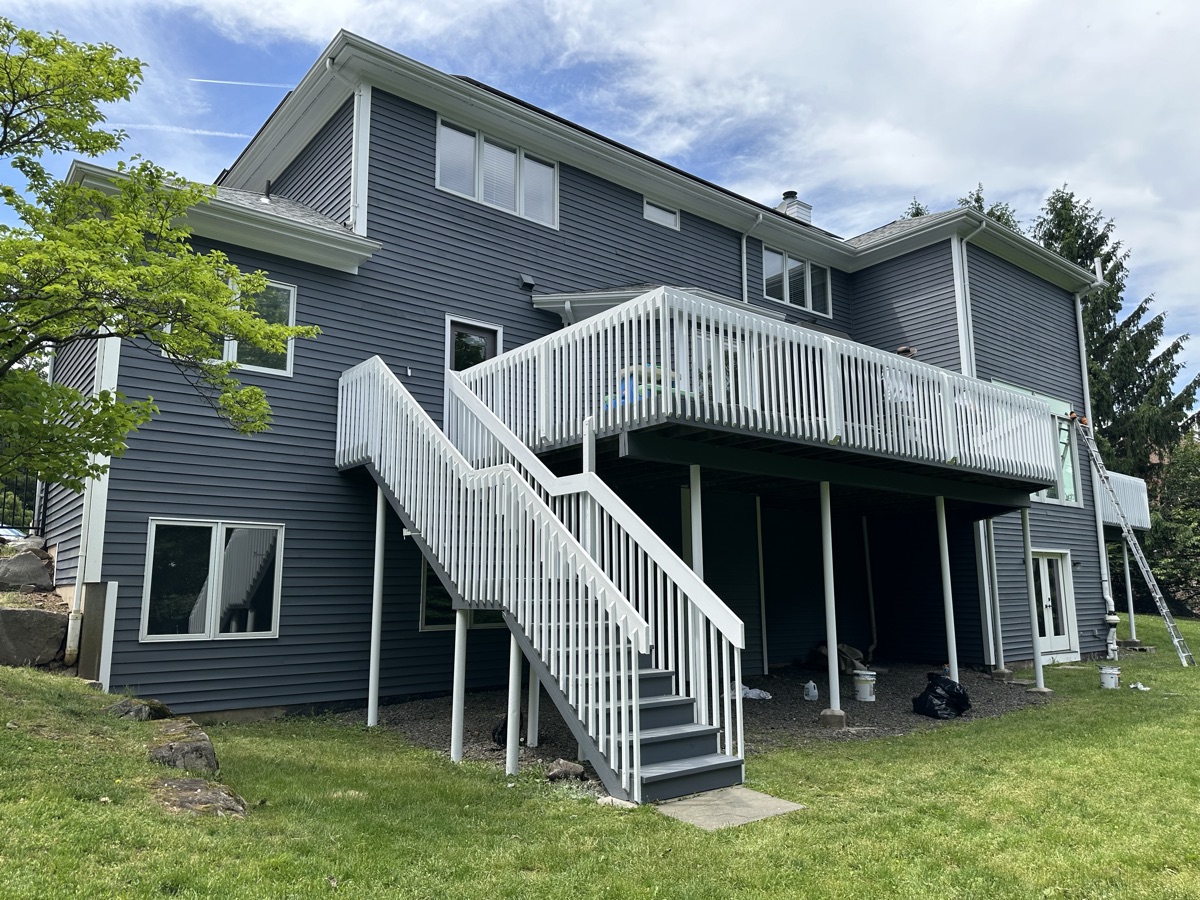 Gray home with white painted deck stairs and railings by J&B Painting