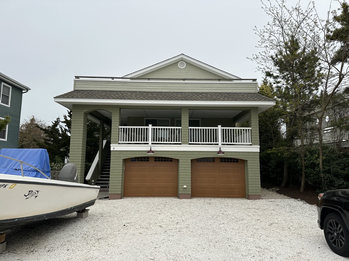 Green coastal home with wood garage doors by J&B Painting