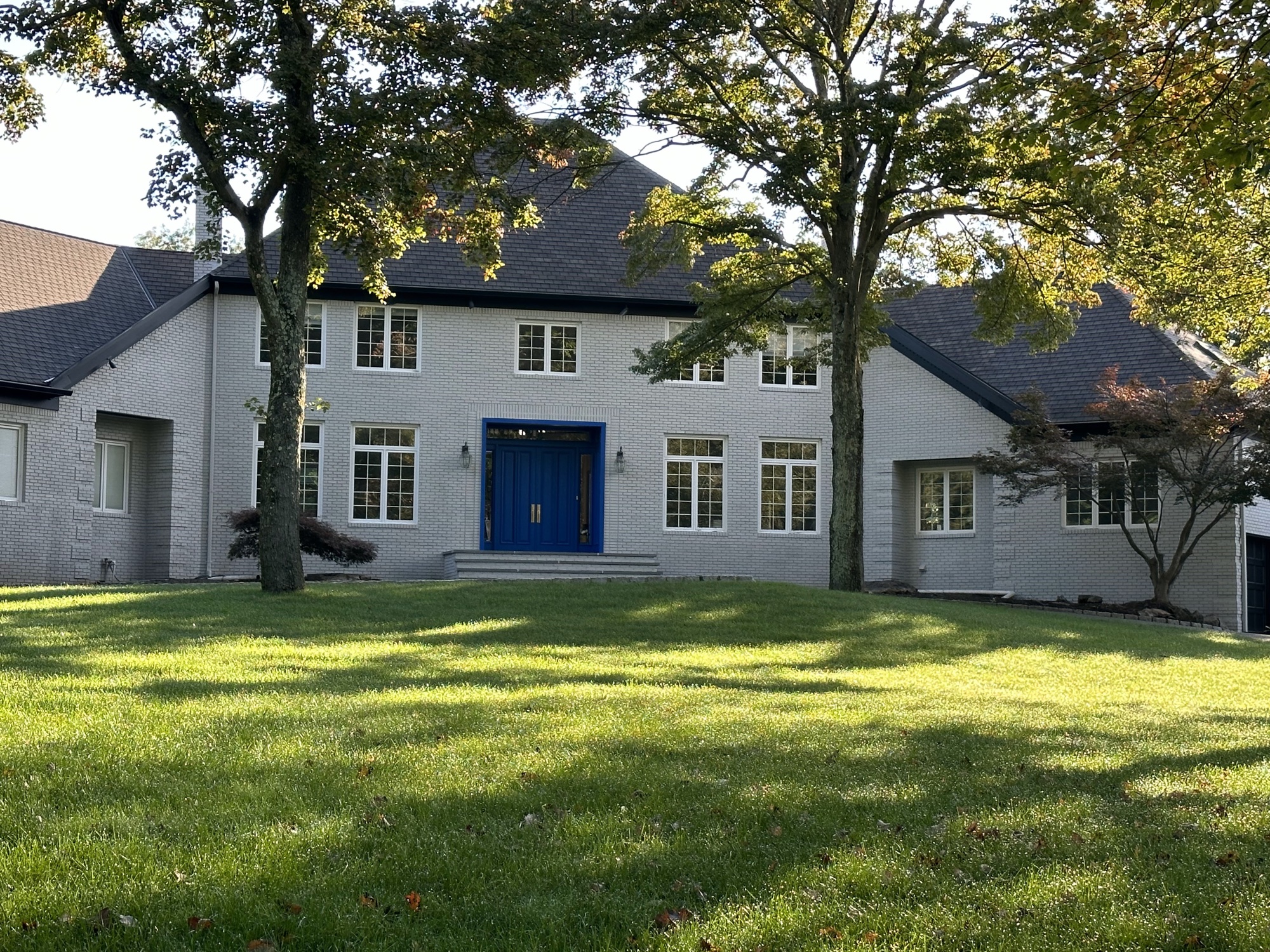 Gray painted brick estate with blue front door by J&B Painting